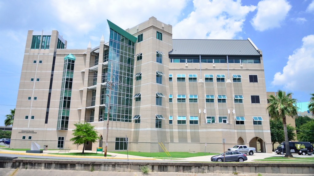 The Norman C. Francis Science Complex, a large five-story Xavier campus building featuring stone arches and large windows and flanked by palm trees. Photo by Valerio de Angelis.